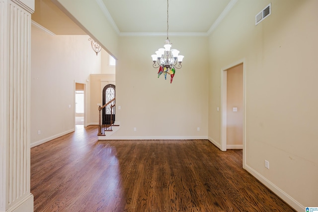 empty room featuring baseboards, visible vents, wood finished floors, an inviting chandelier, and crown molding