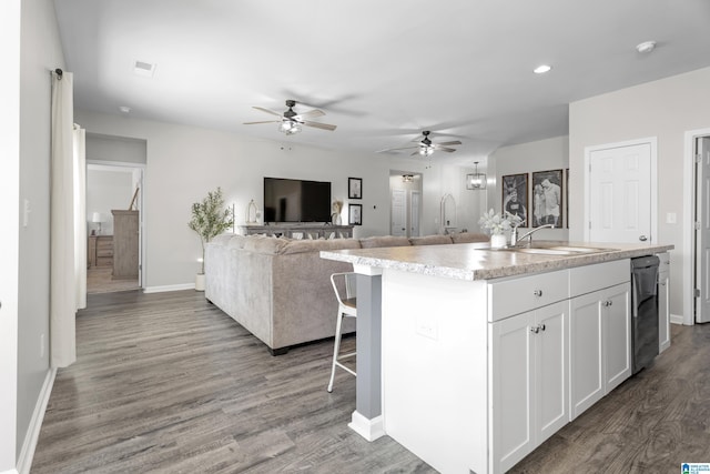 kitchen featuring visible vents, wood finished floors, light countertops, white cabinetry, and a sink