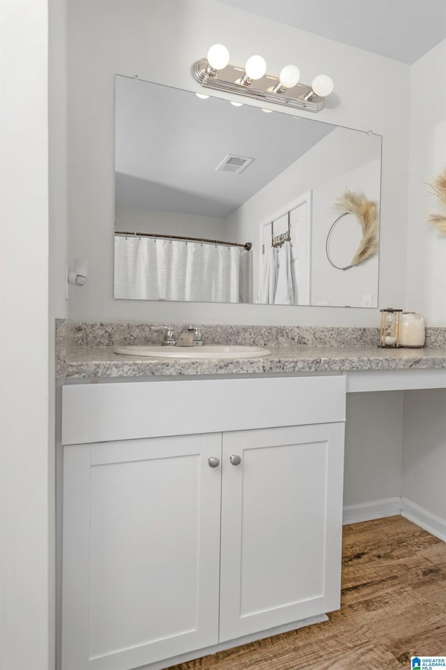 bathroom featuring visible vents, vanity, baseboards, and wood finished floors