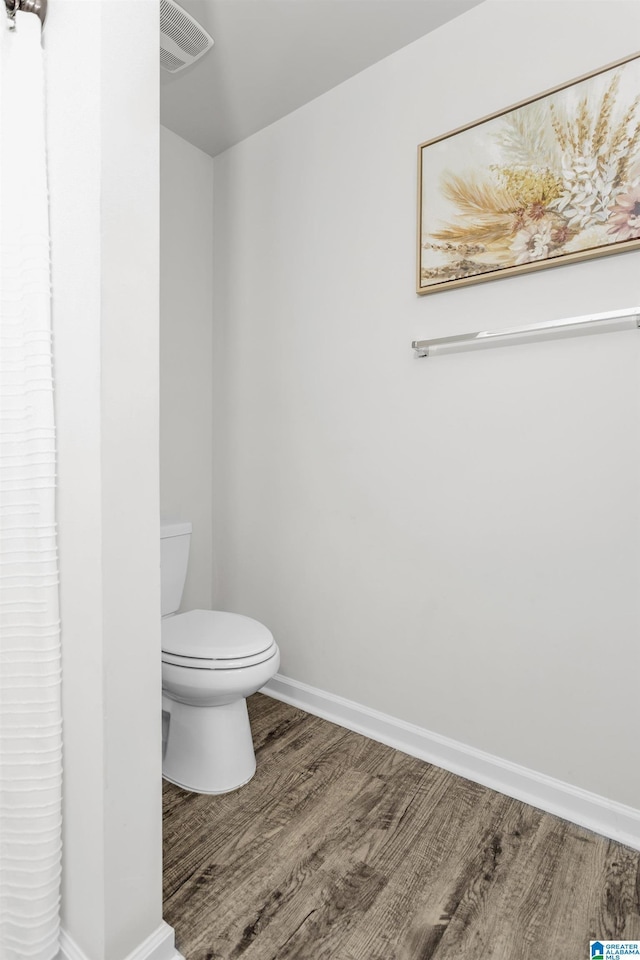 bathroom with visible vents, wood finished floors, toilet, and baseboards