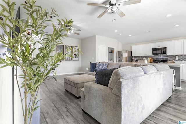 living area with light wood-type flooring, baseboards, vaulted ceiling, and recessed lighting