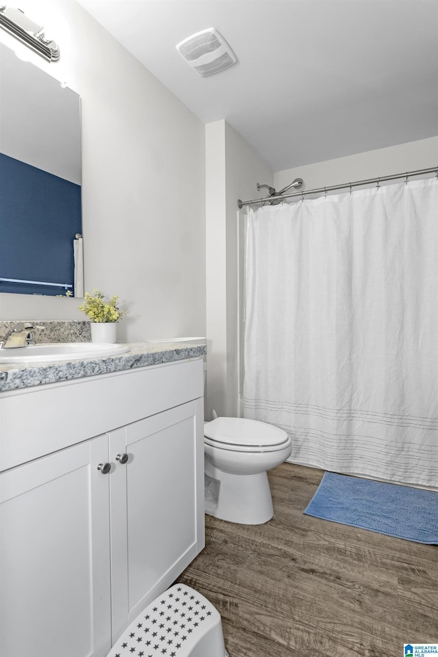 bathroom with visible vents, toilet, wood finished floors, curtained shower, and vanity