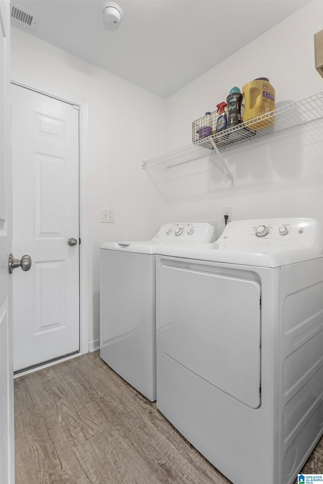 laundry area with light wood-type flooring, laundry area, visible vents, and independent washer and dryer