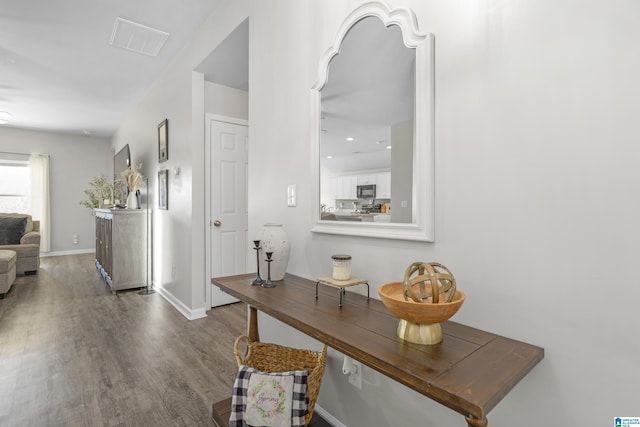 hall featuring wood finished floors, visible vents, and baseboards