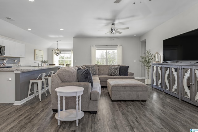 living area featuring recessed lighting, ceiling fan with notable chandelier, dark wood-style flooring, visible vents, and baseboards