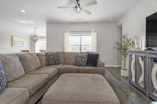 living room featuring dark wood-style floors, baseboards, and ceiling fan with notable chandelier