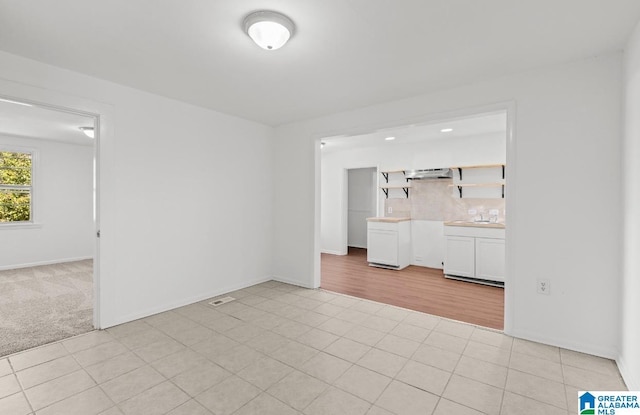 spare room featuring light tile patterned flooring and baseboards