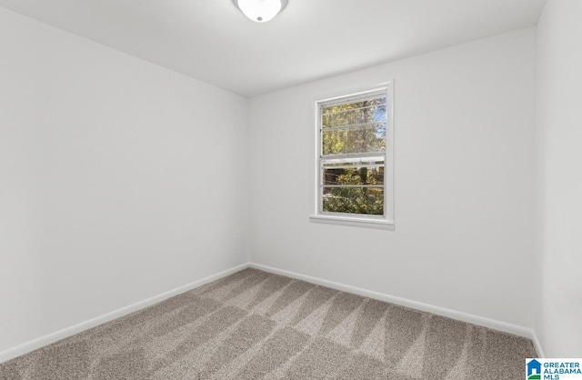 carpeted spare room featuring baseboards