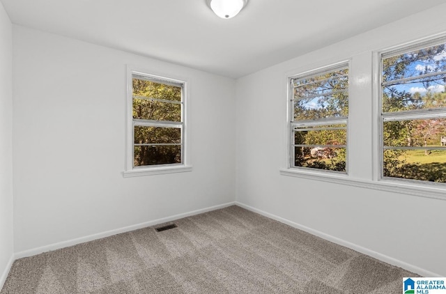 spare room featuring carpet floors, visible vents, and baseboards