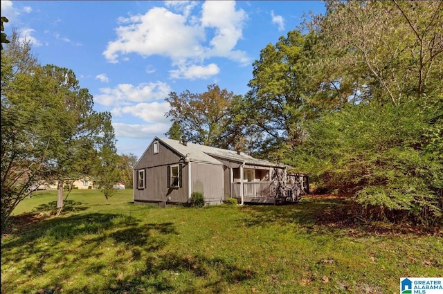 view of side of home with a deck and a lawn