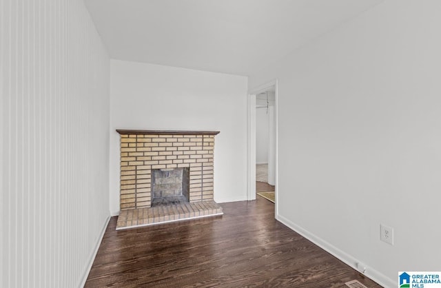 unfurnished living room with a fireplace, baseboards, and wood finished floors