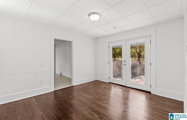 spare room featuring french doors, visible vents, a drop ceiling, and wood finished floors