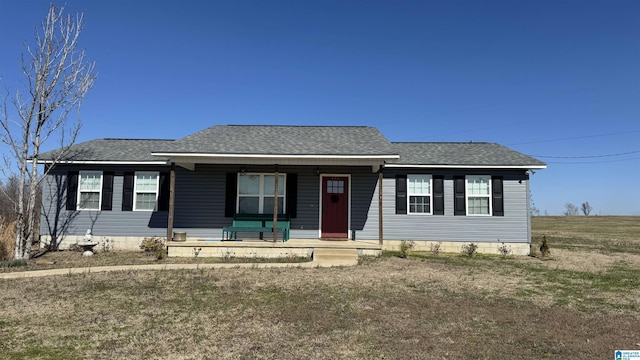 ranch-style house featuring covered porch, a front yard, and roof with shingles