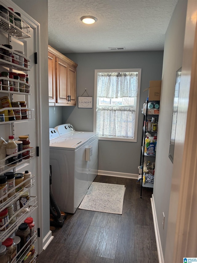 laundry room featuring cabinet space, dark wood finished floors, a textured ceiling, and independent washer and dryer