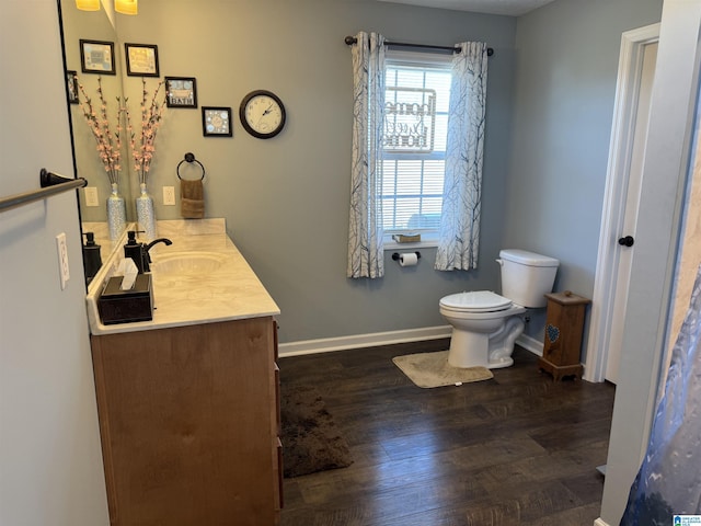 bathroom with toilet, wood finished floors, vanity, and baseboards