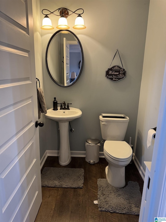 bathroom featuring baseboards, a sink, toilet, and wood finished floors