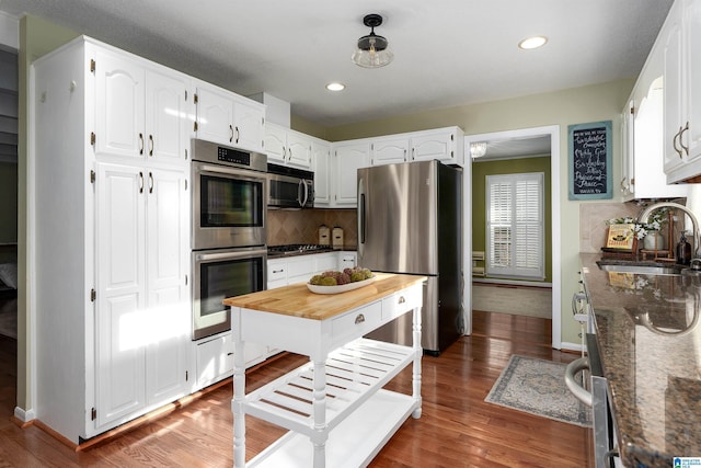 kitchen featuring wood finished floors, appliances with stainless steel finishes, a sink, and tasteful backsplash