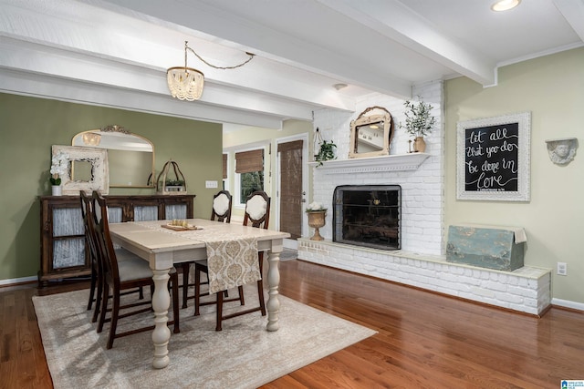 dining area with a brick fireplace, beam ceiling, baseboards, and wood finished floors