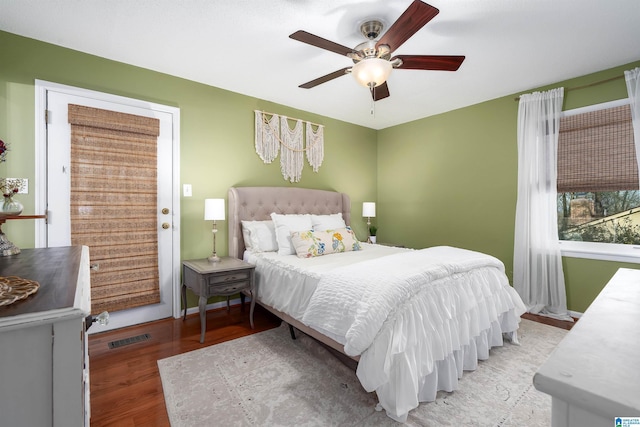 bedroom with a ceiling fan, baseboards, visible vents, and wood finished floors