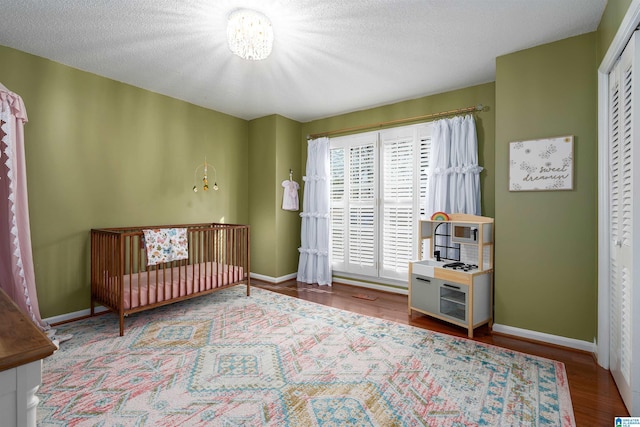 bedroom featuring a textured ceiling, baseboards, and wood finished floors