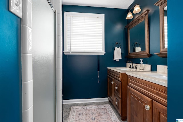 full bathroom featuring double vanity, a sink, a shower with door, and baseboards