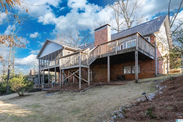 back of house with brick siding, a chimney, a shingled roof, a sunroom, and a deck