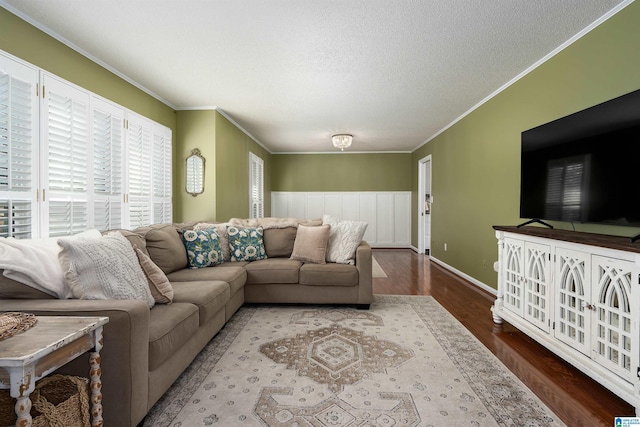 living room featuring a textured ceiling, ornamental molding, wood finished floors, and baseboards