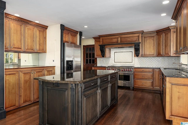 kitchen featuring a sink, stainless steel appliances, dark wood-style floors, and dark stone counters