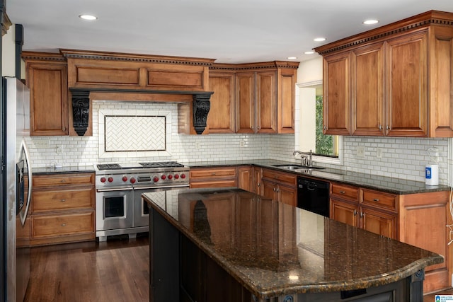 kitchen featuring brown cabinets, dark wood-style flooring, a sink, stainless steel appliances, and tasteful backsplash