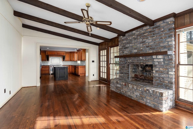 unfurnished living room with a wealth of natural light, lofted ceiling with beams, dark wood-style flooring, and a ceiling fan