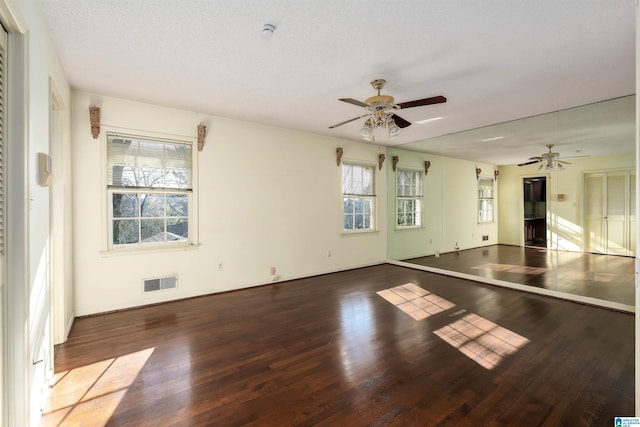 unfurnished room featuring a textured ceiling, wood finished floors, visible vents, and ceiling fan