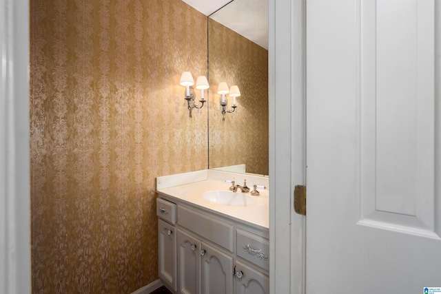 bathroom featuring wallpapered walls, a notable chandelier, and vanity