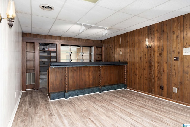 bar featuring visible vents, rail lighting, wooden walls, and wood finished floors