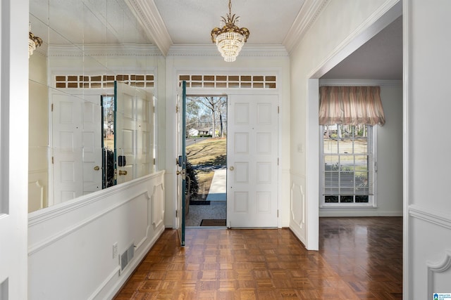 foyer with a notable chandelier, visible vents, crown molding, and baseboards