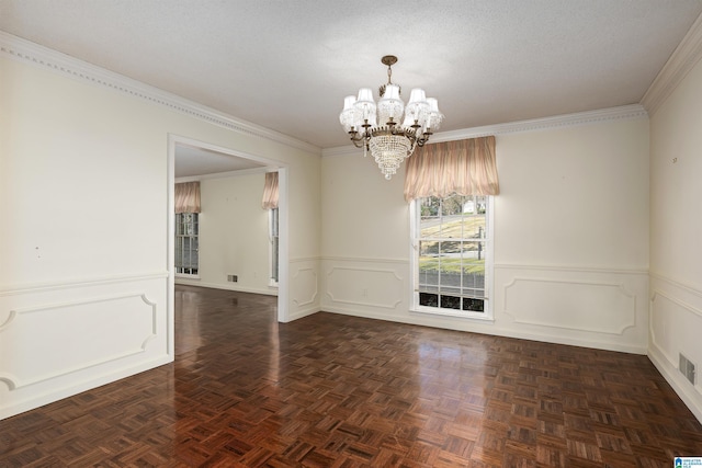 unfurnished room featuring ornamental molding, a notable chandelier, wainscoting, and a textured ceiling