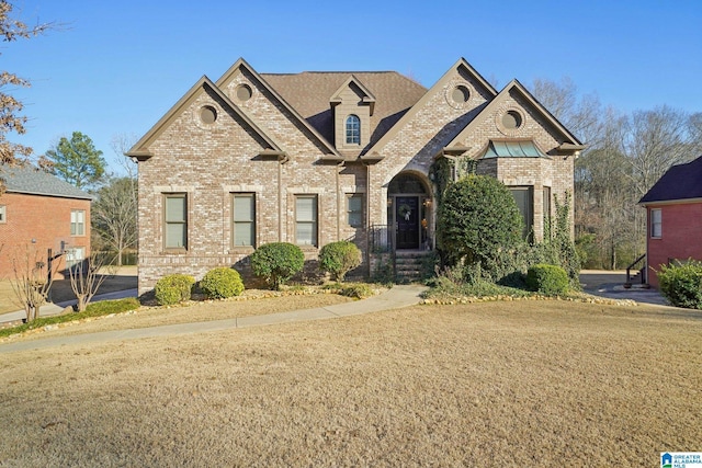 french country inspired facade featuring a front yard and brick siding