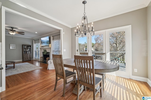 dining space with a fireplace with flush hearth, ornamental molding, wood finished floors, and baseboards