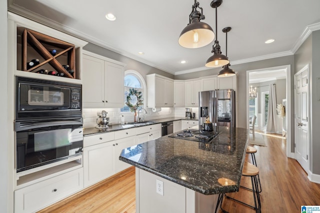 kitchen featuring black appliances, a breakfast bar area, decorative backsplash, and a sink