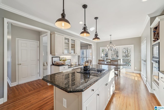 kitchen with ornamental molding, light wood finished floors, glass insert cabinets, and black electric cooktop