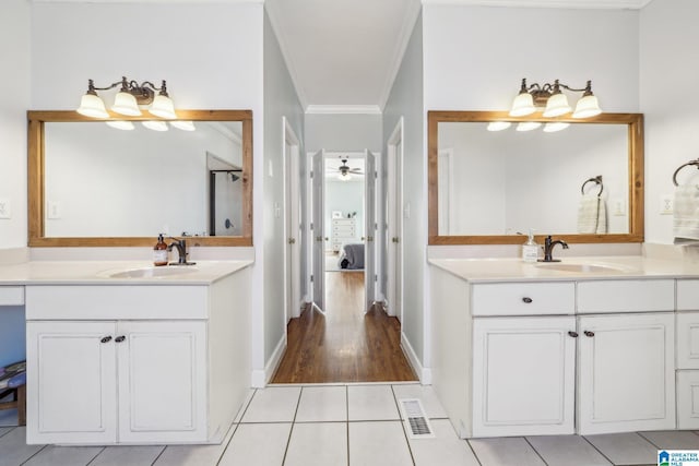 bathroom featuring ornamental molding, two vanities, a sink, and ensuite bathroom