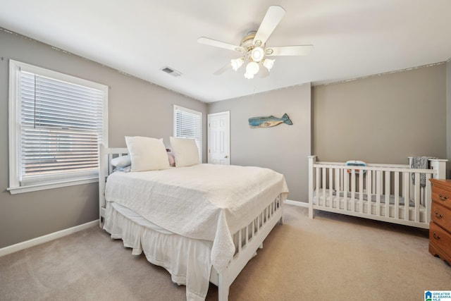 carpeted bedroom with a ceiling fan, visible vents, and baseboards