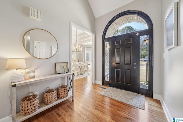 entrance foyer with lofted ceiling, a wealth of natural light, visible vents, and wood finished floors