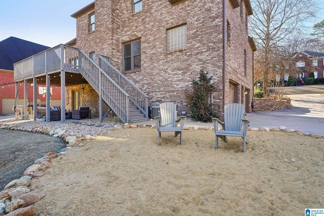 exterior space featuring a garage, brick siding, driveway, stairway, and a wooden deck