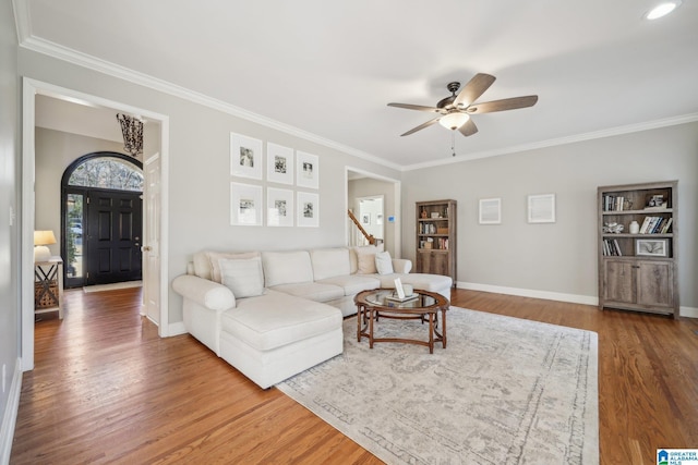 living area with baseboards, wood finished floors, and crown molding