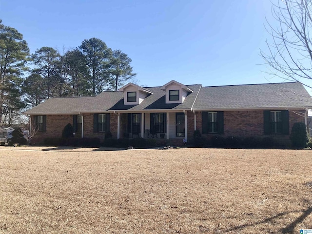 view of front of home featuring brick siding, a shingled roof, and a front lawn