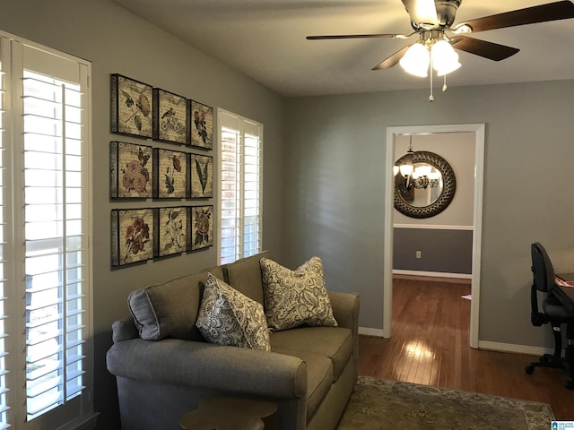 office featuring baseboards, wood finished floors, and ceiling fan with notable chandelier