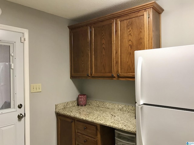 kitchen featuring freestanding refrigerator and light stone countertops