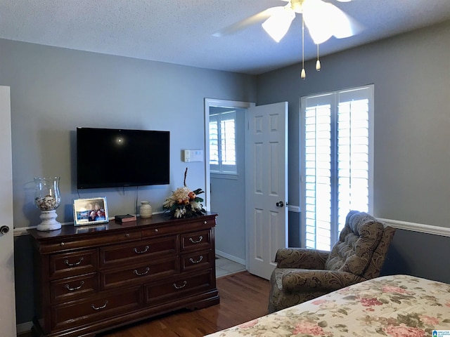 bedroom with a textured ceiling, dark wood-style floors, and a ceiling fan