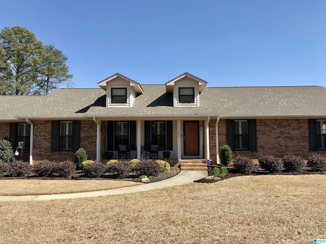 view of front of house with brick siding, a porch, and a shingled roof