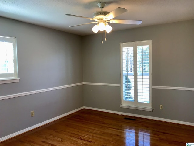 unfurnished room with visible vents, plenty of natural light, baseboards, and wood finished floors